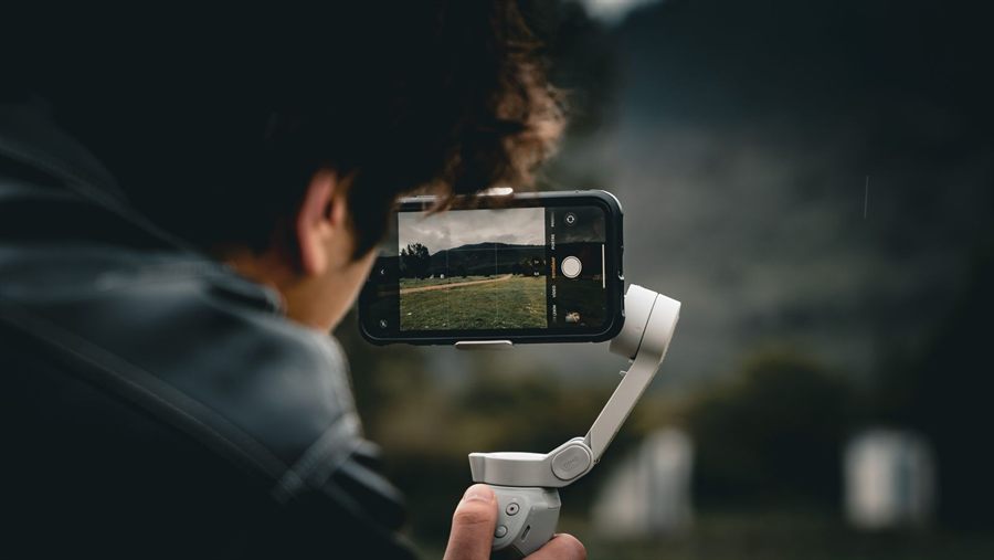 A traveller filming a landscape with a phone on a handheld gimbal
