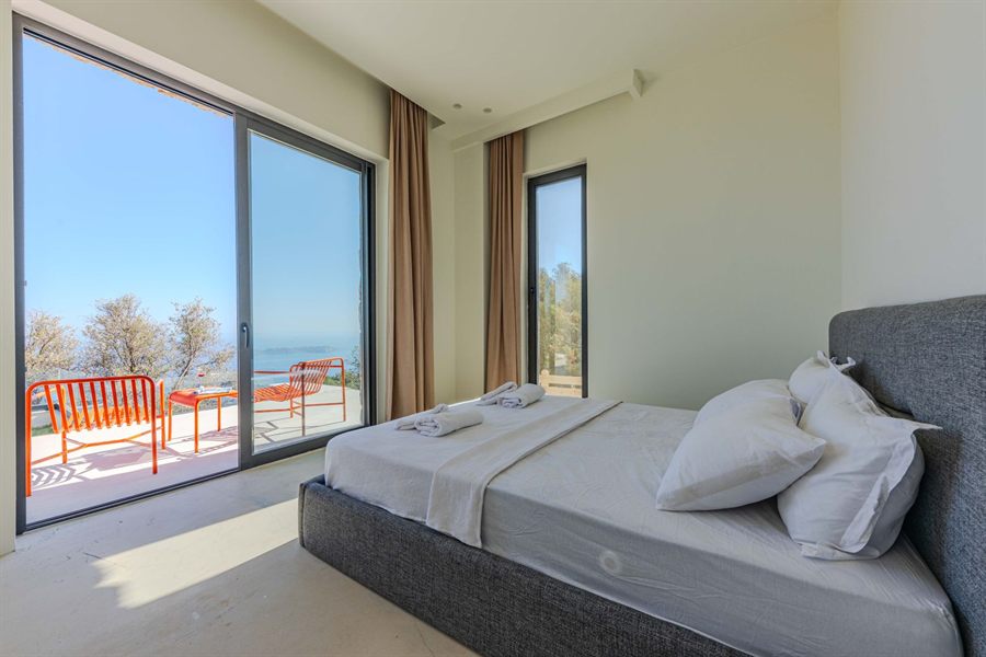 A bright bedroom with sliding doors open to a sunny sea-view balcony