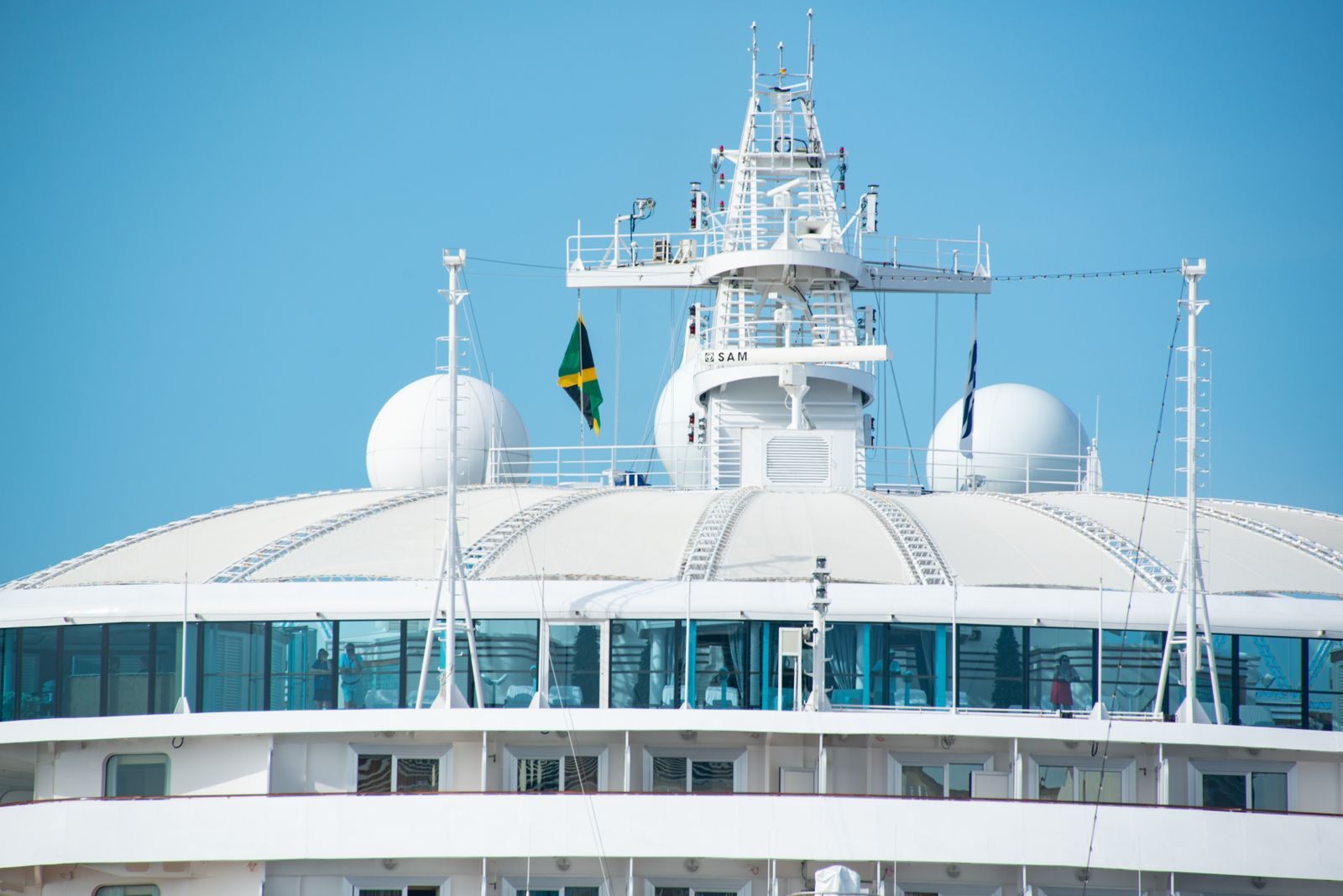 The white upper decks and radar domes of a cruise ship under a blue sky, the kind of ship cruise line reviews and ratings score