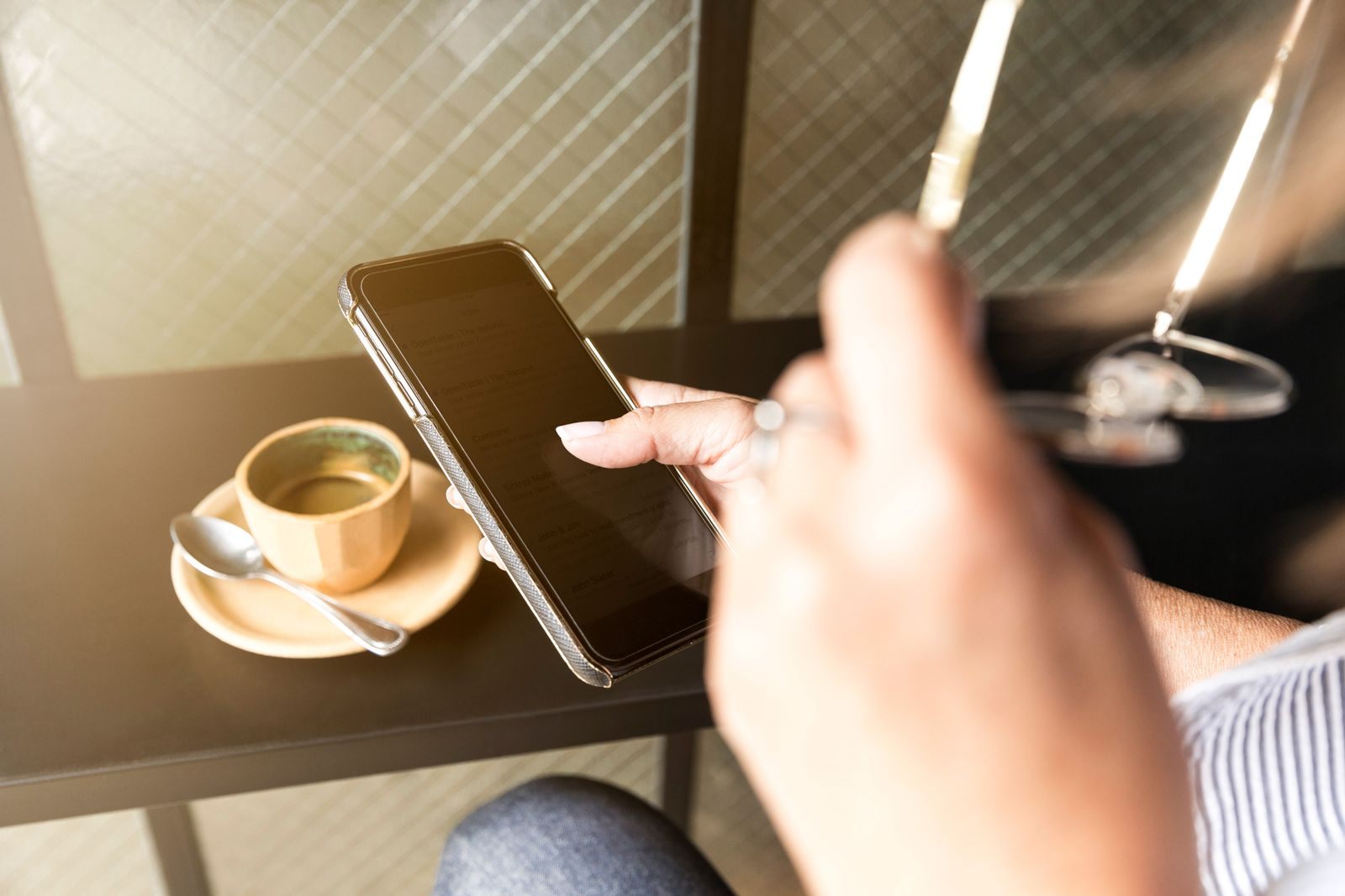 A hand scrolling a phone next to a cup of coffee, like reading cruise reviews on Tripadvisor