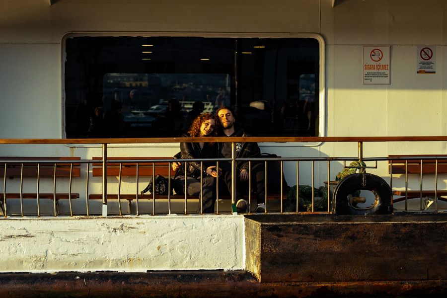 A couple sitting together on the open deck of a passenger ship in the evening sun