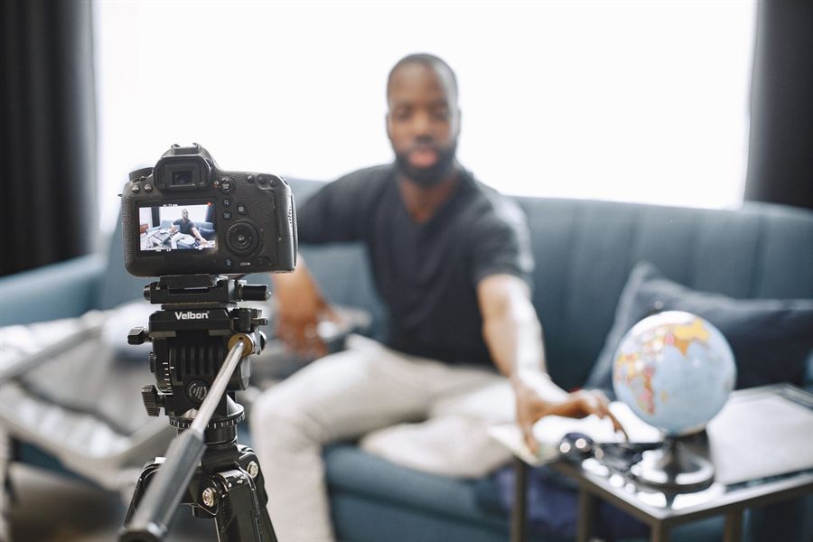 A video creator setting up a camera on a tripod to record at home